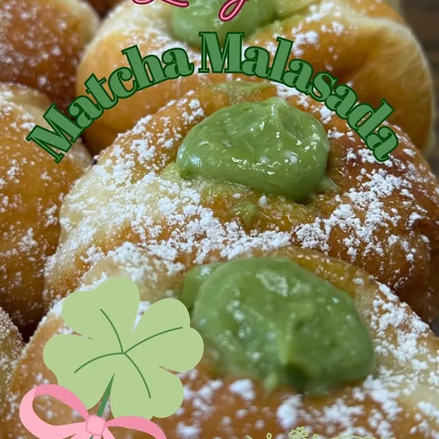 A matcha cream malasada dusted with powdered sugar